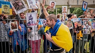 جندي أوكراني محرَّر يلوّح لمدنيين أوكرانيين يحملون صور أقاربهم المفقودين، شمال أوكرانيا، الجمعة 20 حزيران/يونيو 2025.