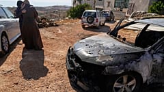 Üç Filistinlinin ölümüne neden olan saldırıda İsrailli yerleşimciler tarafından yakılan bir aracın yanında kadınlar birbirlerini teselli ediyor