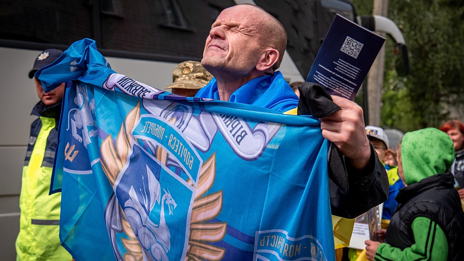 Um soldado ucraniano libertado segura a bandeira da sua unidade após uma troca de prisioneiros de guerra com a Rússia