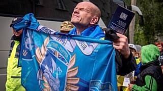 Um soldado ucraniano libertado segura a bandeira da sua unidade após uma troca de prisioneiros de guerra com a Rússia