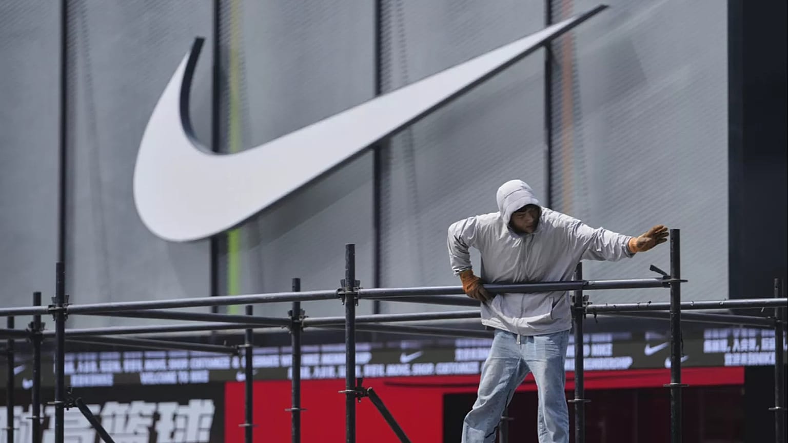 Un operaio installa una piattaforma vicino a un negozio Nike fuori da un centro commerciale a Pechino, domenica 11 maggio 2025.
