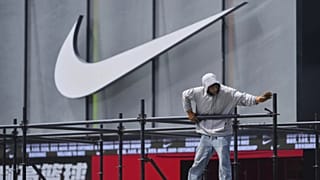 Un trabajador instala una plataforma cerca de una tienda Nike en el exterior de un centro comercial en Pekín, el domingo 11 de mayo de 2025.