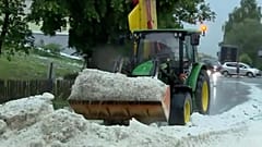 Eine Maschine räumt Hagelkörner von der Straße
