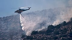 Ein Löschhubschrauber wirft Wasser ab, während er einen Brand in der Küstengegend von Charakas, südlich von Athen, bekämpft, Donnerstag, 26. Juni 2025,
