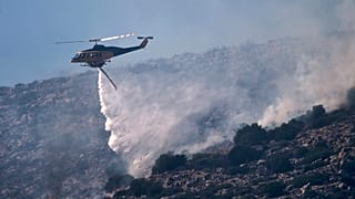 Πυροσβεστικό ελικόπτερο ρίχνει νερό κατά τη διάρκεια κατάσβεσης πυρκαγιάς στην παραθαλάσσια περιοχή του Χάρακα, νότια της Αθήνας, Πέμπτη 26 Ιουνίου 2025,
