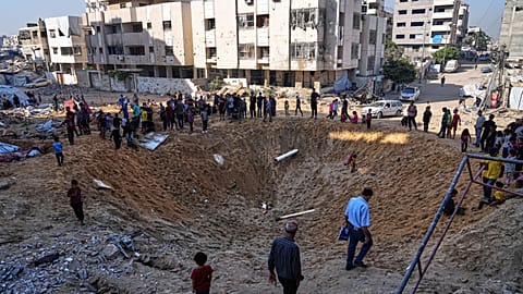 Palestinians gather around a crater caused by an Israeli strike on a displacement tent camp in Gaza City, 28 June 2025