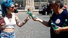 Ein freiwilliger Helfer des Katastrophenschutzes verteilt kostenlose Wasserflaschen an Touristen neben dem Kolosseum in Rom, Donnerstag, 12. August 2021