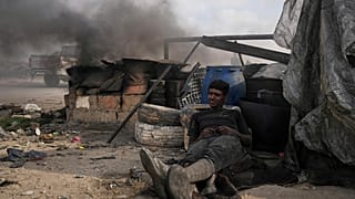 يستريح محمد نجم أثناء عمله على موقد مؤقت يستخدمه لاستخراج الوقود من البلاستيك المذاب، جنوب مدينة غزة، الأحد 22 يونيو 2025.  
