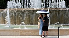 Turistler Milano'daki Sforzesco Kalesi'nde bir çeşmenin yanında sıcak güneşten korunuyor.