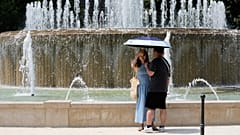 Touristen schützen sich vor der heißen Sonne an einem Brunnen im Schloss Sforzesco in Mailand.
