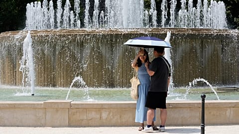 Tourists shelter from the hot sun next to a fountain at the Sforzesco Castle in Milan.