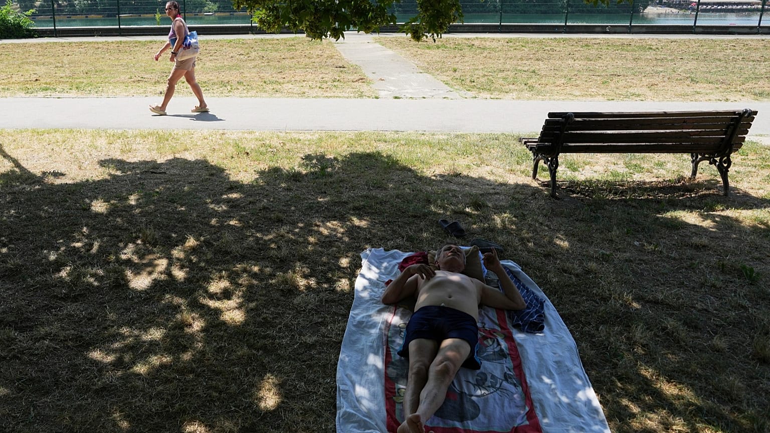 Ein Mann ruht sich an einem warmen und sonnigen Tag am See Ada Ciganlija in Belgrad, Serbien, im Schatten aus, Donnerstag, 26. Juni 2025.