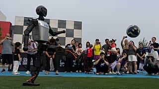 An AI-powered humanoid robot demonstrates kicking a football at a competition held in Beijing on June 28, 2025.