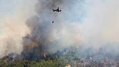 Ein Hubschrauber sprüht Wasser, um ein Feuer in Seferihisar nahe Izmir, Türkei zu löschen.