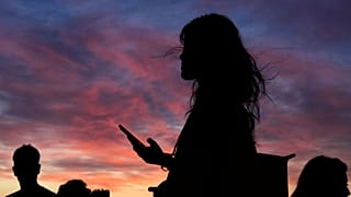 Ludzie oglądają zachód słońca z punktu z widokiem na Lizbonę pod koniec upalnego dnia, piątek, 27 czerwca 2025 r.