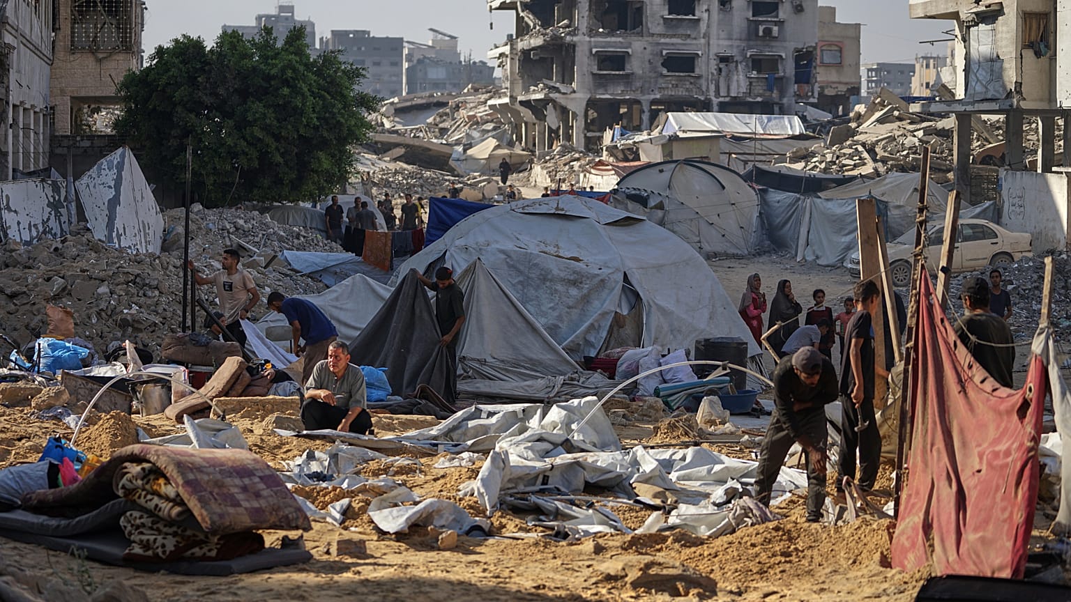Palestinesi ispezionano le tende danneggiate dopo che un attacco israeliano ha colpito un campo di sfollati a Gaza City, sabato 28 giugno 2025.