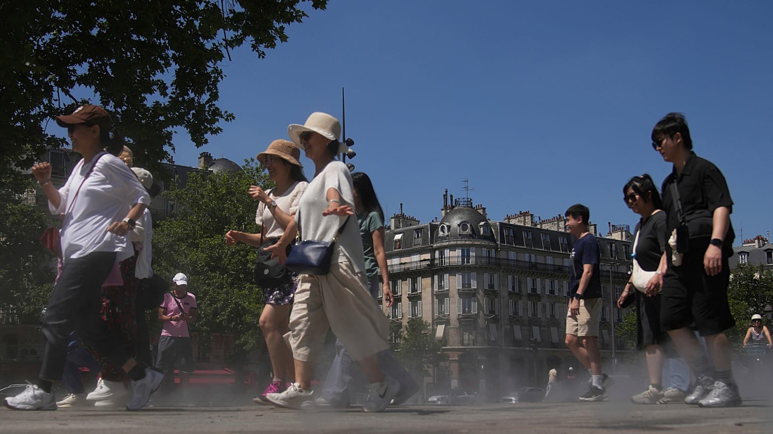 I turisti camminano attraverso una fresca vaporizzazione d'acqua durante un test di nebulizzazione, durante un'ondata di caldo lunedì 30 giugno 2025 a Parigi