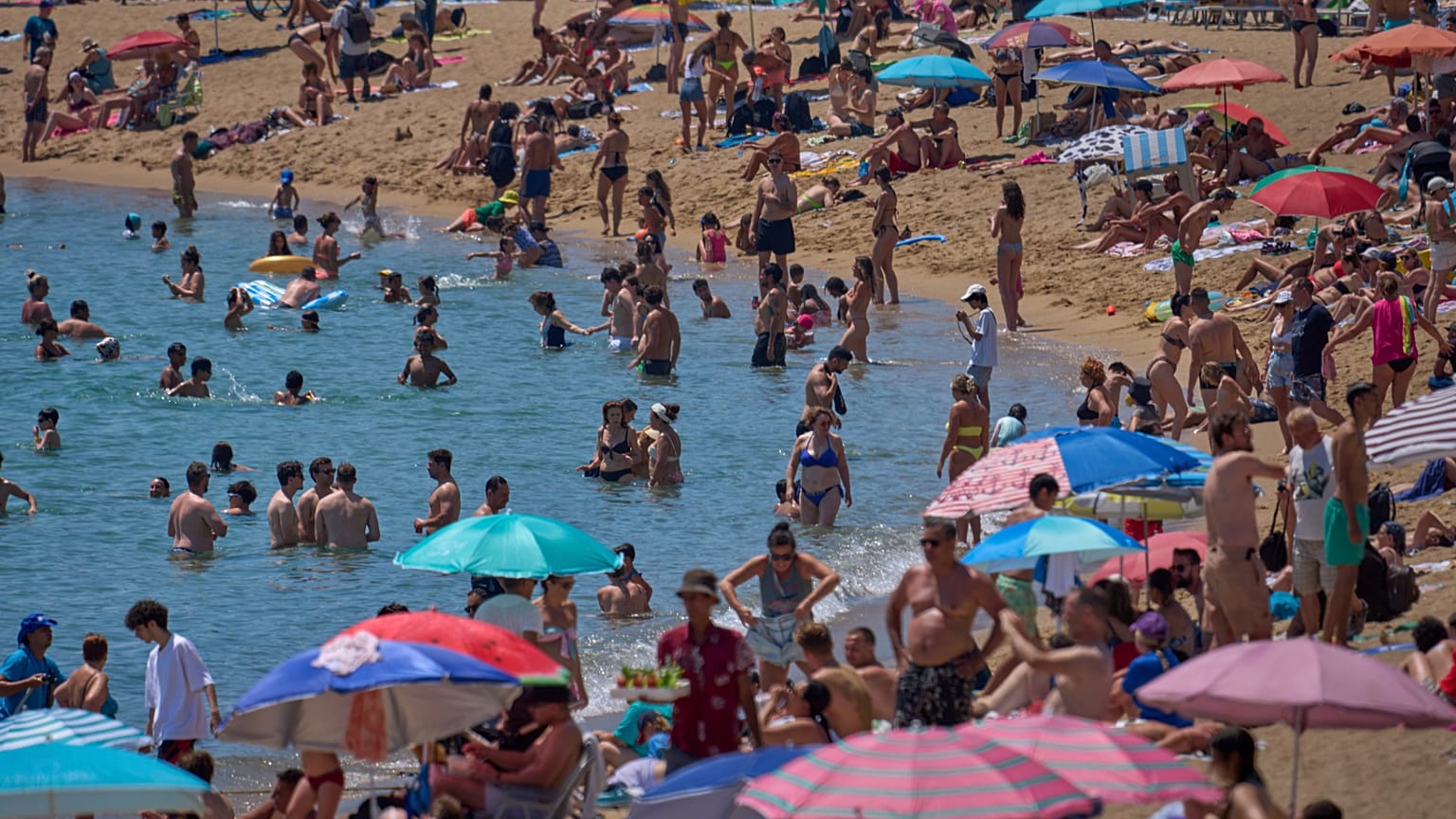 Купальщики охлаждаются в воде на пляже в жаркий день в Барселоне, Испания, суббота, 28 июня 2025 года.