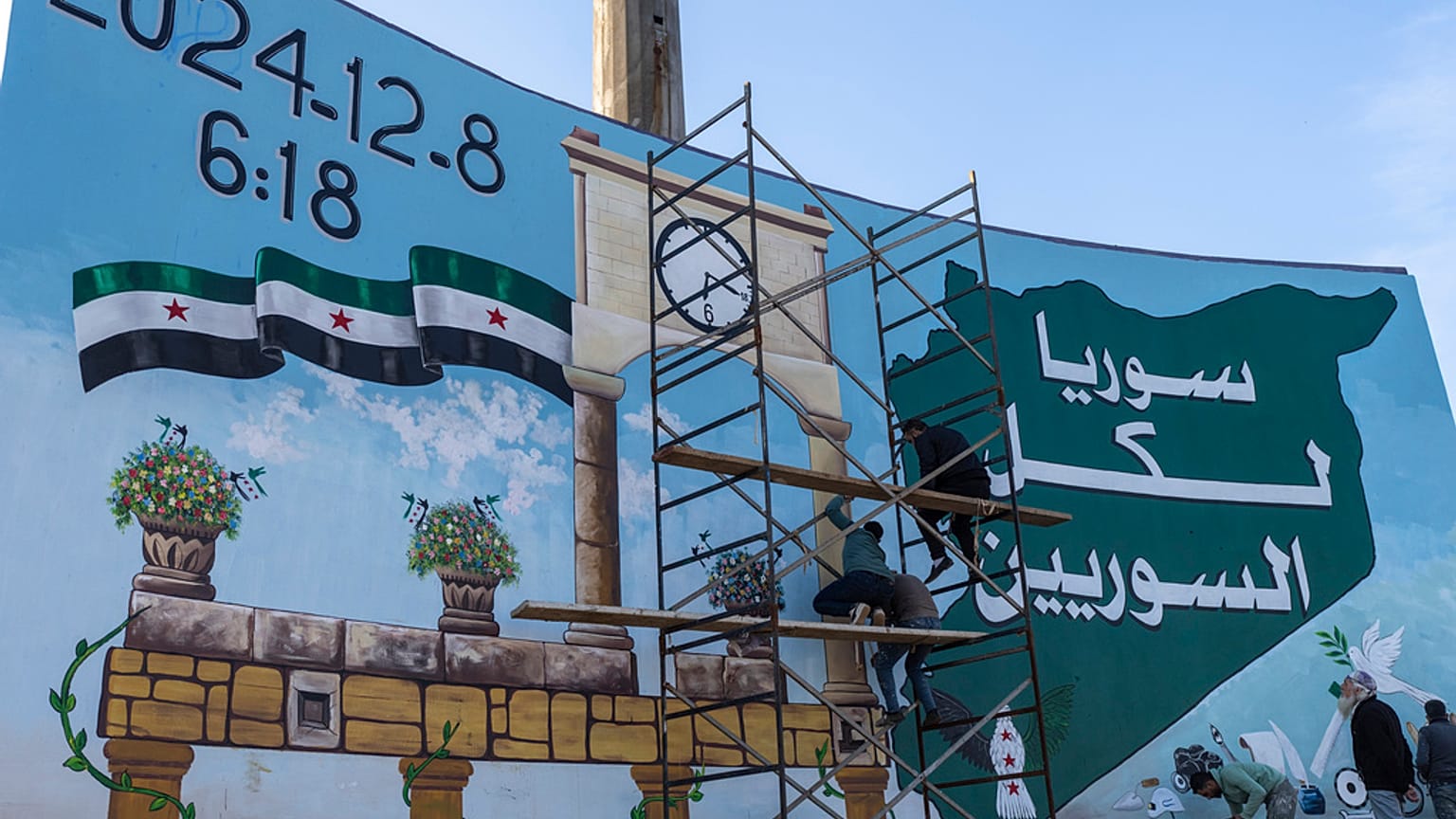 متطوعون يرسمون "جرافيتي النصر" في الساحة الرئيسية بإدلب، سوريا
