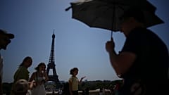 People walk at Trocadero plaza near Eiffel Tower during a heatwave on 2 July. 