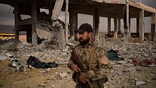 يقف أحد أفراد قوات الأمن التابعة للحكومة السورية المشكلة حديثًا أمام البنية التحتية للأسلحة والعسكرية المتضررة في أعقاب انفجار