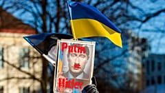 Ein Demonstrant hält eine ukrainische und eine estnische Nationalflagge mit einem Plakat bei einer Kundgebung zur Unterstützung der Ukraine in Tallinn, Estland, Samstag, 26. Februar 2022