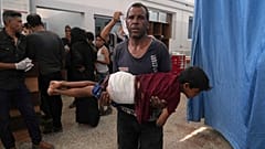رجل يحمل طفلا أصيب في غارة إسرائيلية بعد تلقيه العلاج في مستشفى الشفاء ، مدينة غزة ، الاثنين 30 حزيران / يونيو 2025.