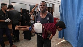 رجل يحمل طفلا أصيب في غارة إسرائيلية بعد تلقيه العلاج في مستشفى الشفاء ، مدينة غزة ، الاثنين 30 حزيران / يونيو 2025.