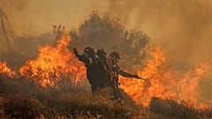 Ein Feuerwehrmann benutzt einen Schlauch, um am Donnerstag, den 3. Juli 2025, das Feuer in der Nähe der Stadt Ierapetra an der Südküste der Insel Kreta, Griechenland, zu löschen.