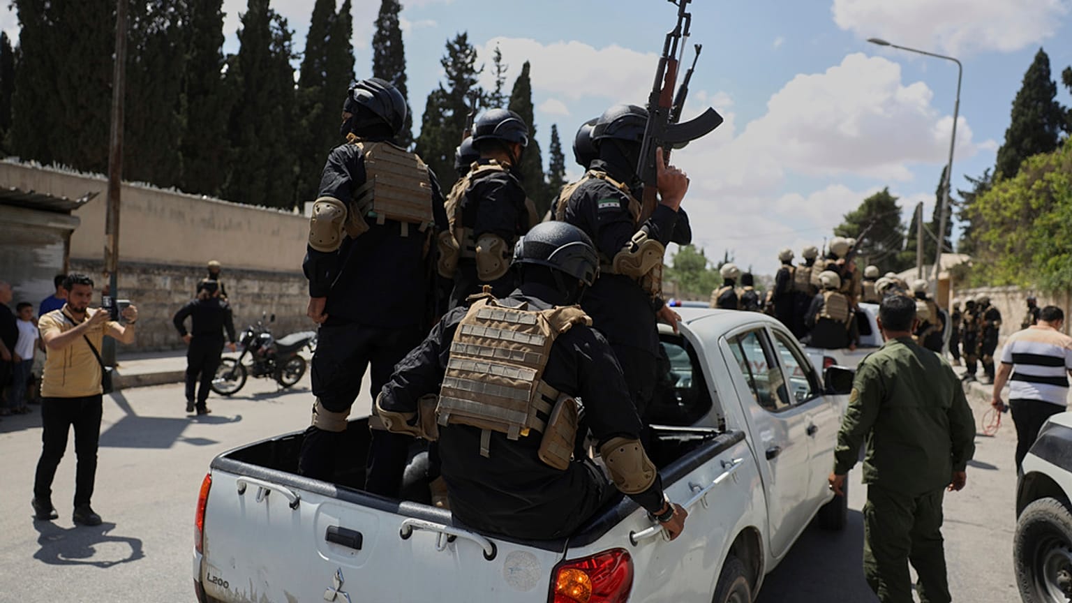 أفراد من قوة أمنية حكومية يركبون في الجزء الخلفي من شاحنة صغيرة أثناء تبادل الأسرى بين السلطات السورية وقوات سوريا الديمقراطية