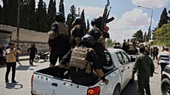 أفراد من قوة أمنية حكومية يركبون في الجزء الخلفي من شاحنة صغيرة أثناء تبادل الأسرى بين السلطات السورية وقوات سوريا الديمقراطية