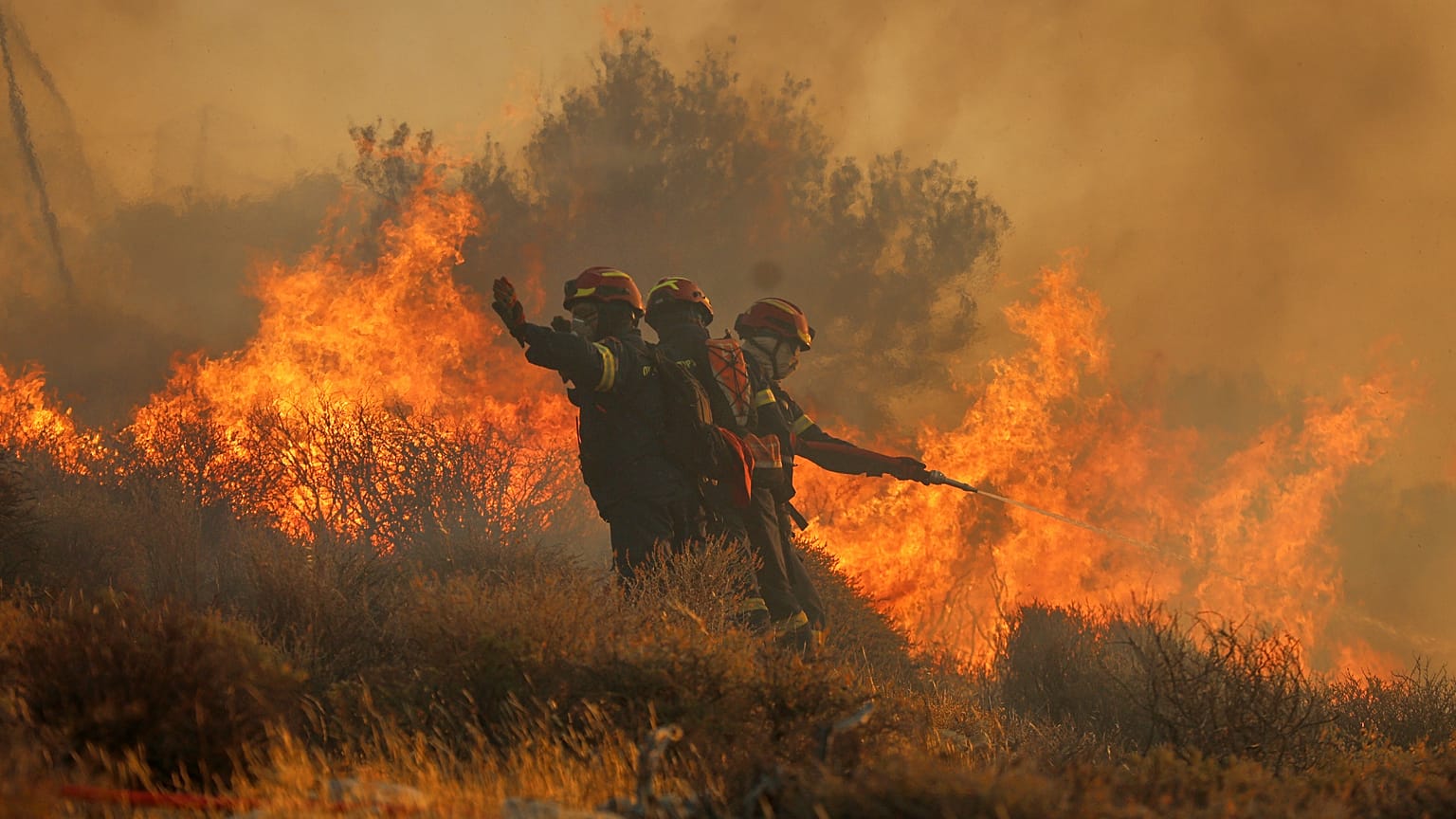 Firefighters use a hose as the try to extinguish a wildfire near the town of Ierapetra on the south coast of Crete, 3 July, 2025