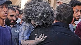 Un uomo porta in braccio un bambino ferito dopo un attacco israeliano contro un edificio residenziale a Gaza City