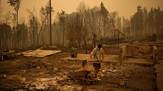 Yeremy Escanilla trabaja en la limpieza de los escombros de los restos de su casa, destruida por los incendios forestales en Santa Juana, Chile, en 2023.