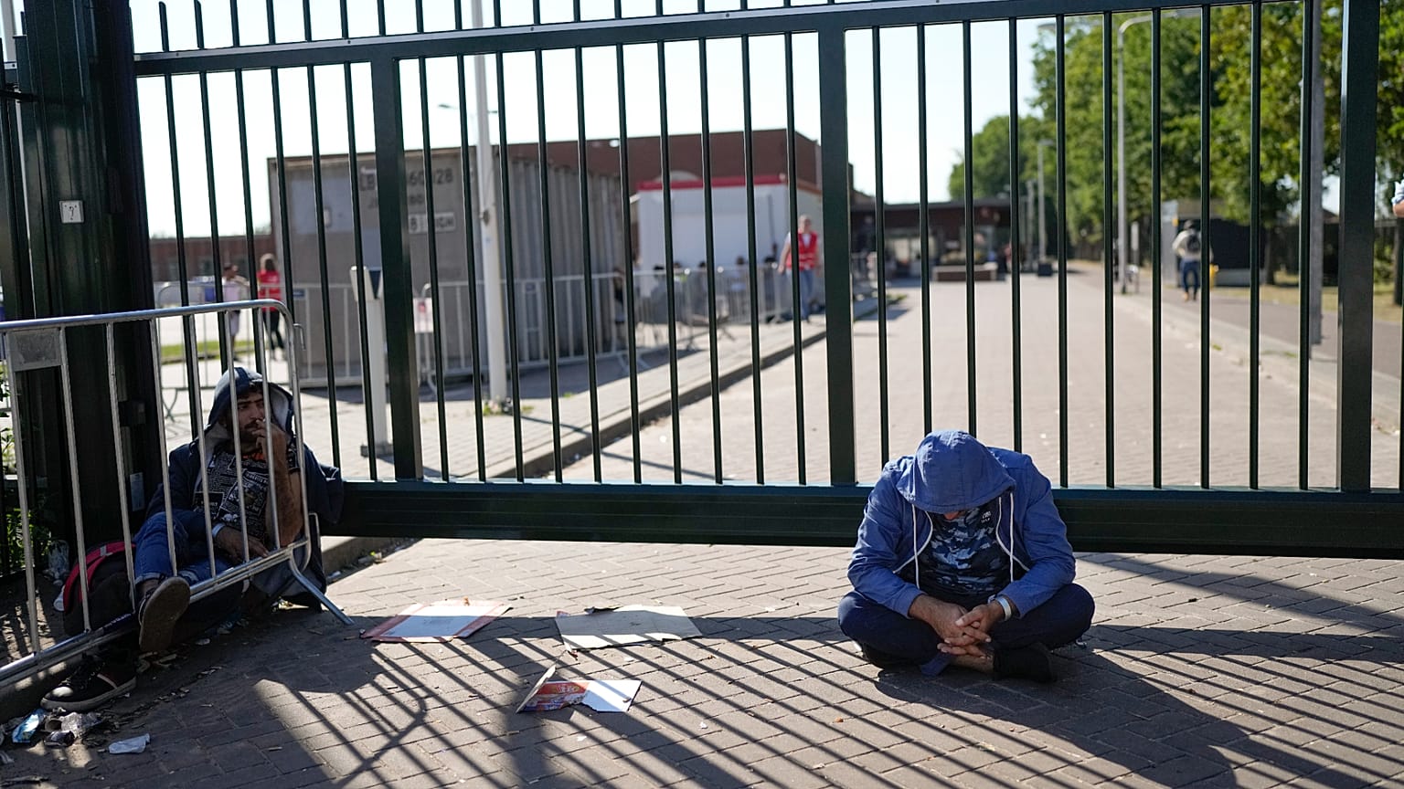 DOSSIER : Un homme est assis devant la porte d'un centre de demandeurs d'asile surpeuplé où des centaines de migrants cherchent refuge à Ter Apel, le 25 août 2021.