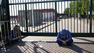 FILE: A man sits outside the gate of an overcrowded asylum seekers center where hundreds of migrants seek shelter in Ter Apel, 25 August 2021