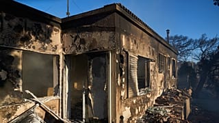 De la fumée est visible à l'intérieur d'une maison brûlée alors qu'un incendie de forêt se propage à Rafina, à l'est d'Athènes, en Grèce, jeudi 3 juillet 2025, plusieurs maisons ayant été détruites dans la région.