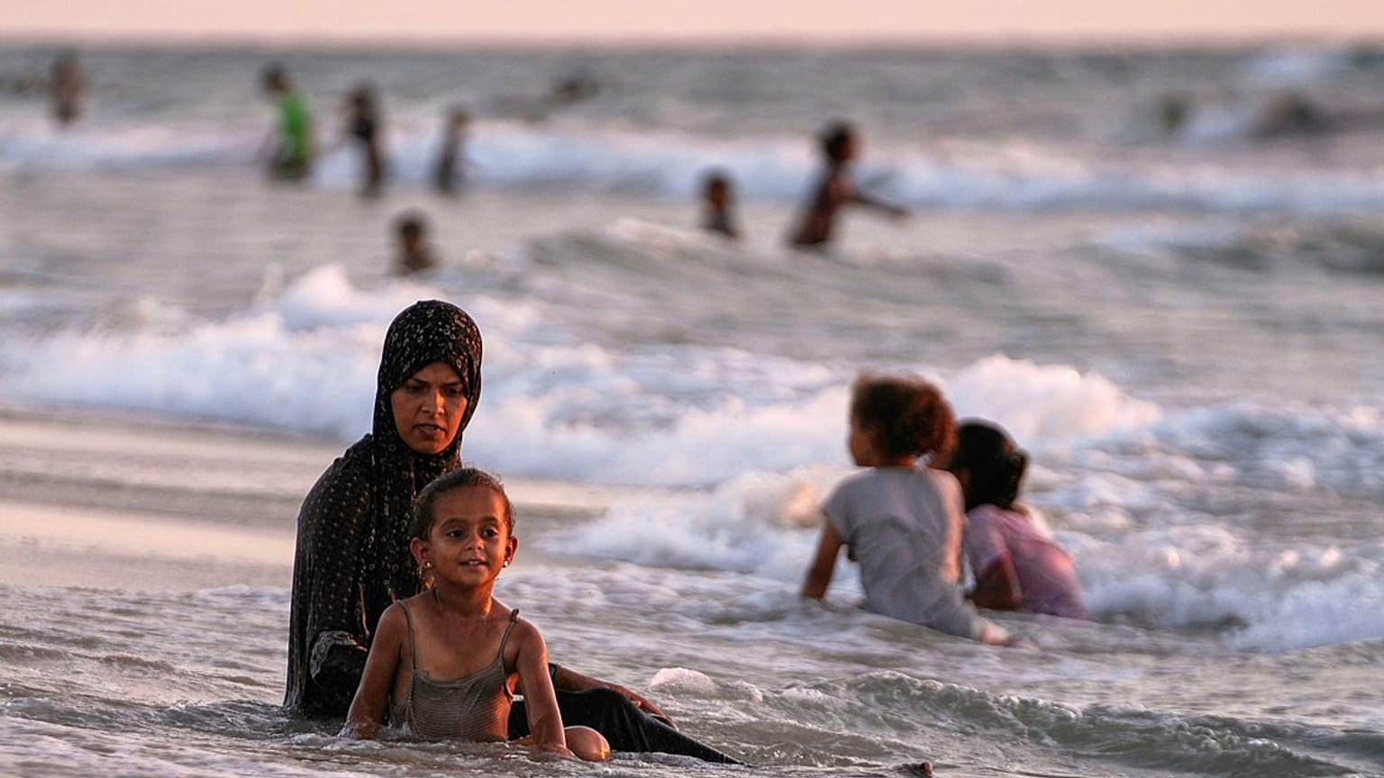 نازحون فلسطينيون يبردون أجسادهم في البحر الأبيض المتوسط ​​خلال موجة الحر في خان يونس، قطاع غزة، الأربعاء 2 يوليو/تموز 2025. 