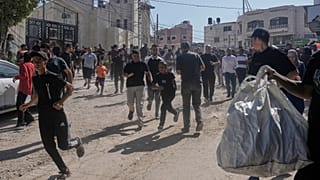 Refugiados palestinos corriendo en un campo.