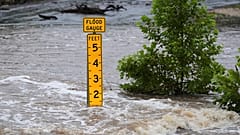 Ein Hochwassermesser zeigt die Höhe des Wassers an, das am Freitag, den 4. Juli 2025, über eine Landstraße in der Nähe von Kerrville, Texas, fließt. 