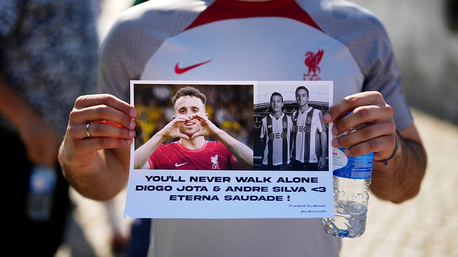 Egy szurkoló egy transzparenst mutat, miközben sorban áll, hogy beléphessen a templomba, ahová a Liverpool támadóinak, Diogo Jotának és André Silvának a holttestét vitték a virrasztásra