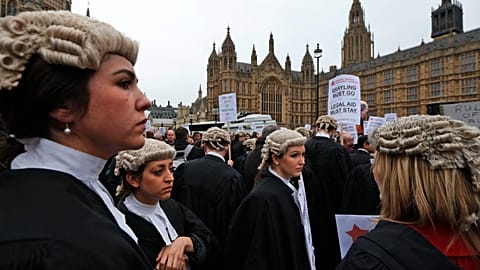 Lawyers hold placards as they participate in a protest against legal aid cuts, across from the Houses of Parliament in London. 7 March 2014.
