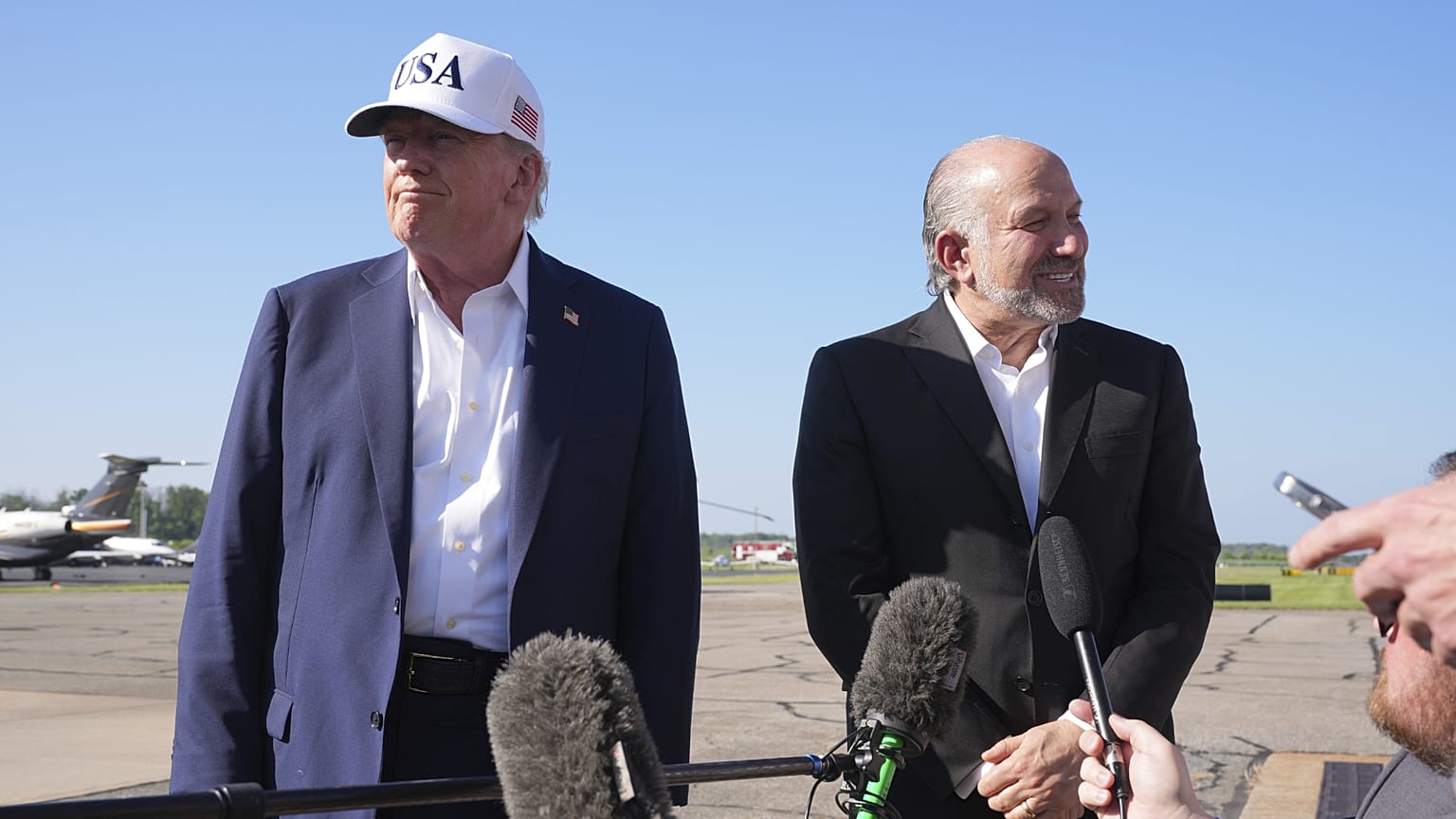 President Donald Trump listens as Commerce Secretary Howard Lutnick speaks with reporters. Morristown Municipal Airport, New Jersey. 6 July 2025.