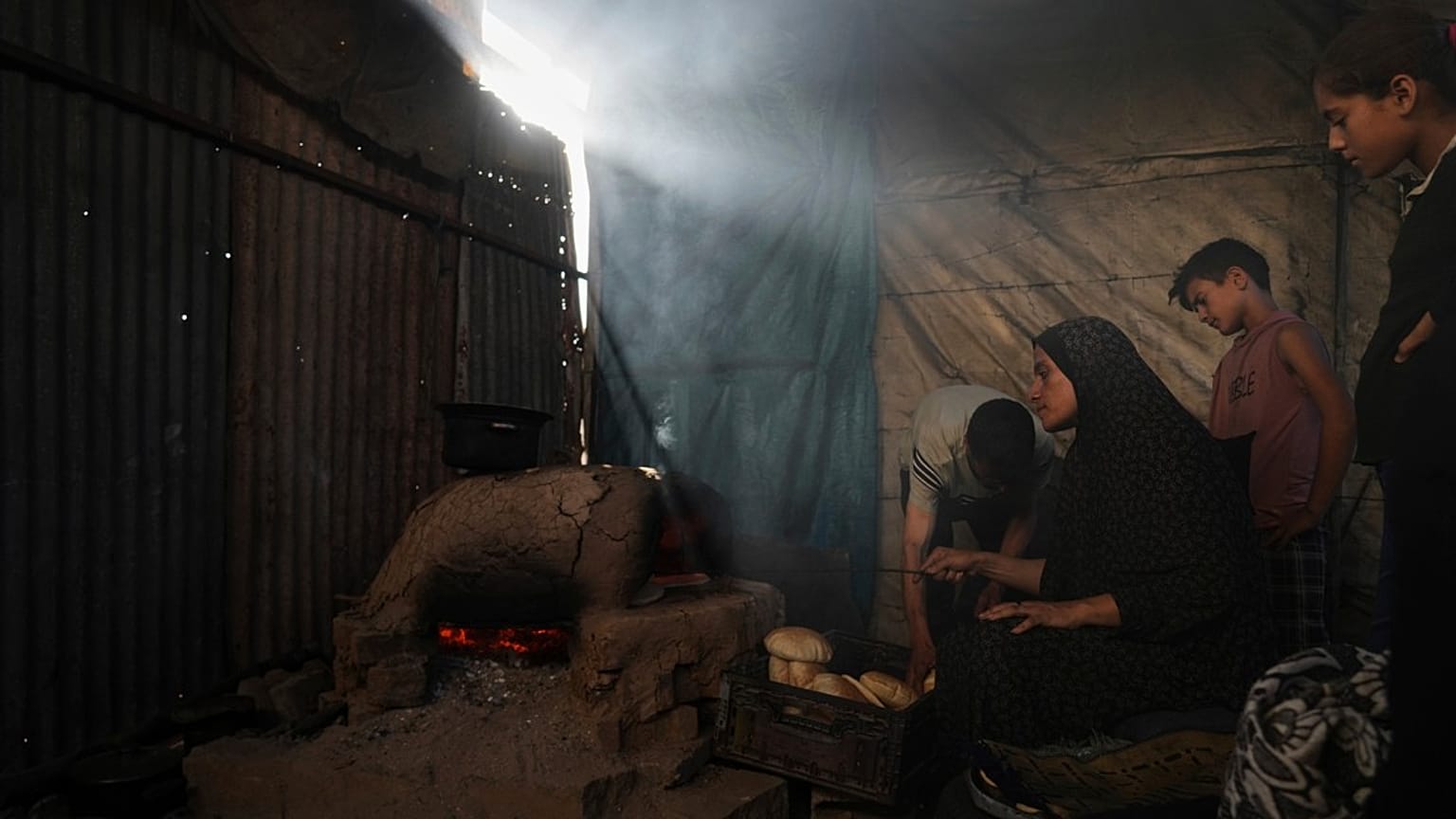 نازحون فلسطينيون يخبزون الخبز في مدرسة تُستخدم الآن كمأوى في دير البلح، قطاع غزة، الأحد 6 يوليو/تموز 2025.  
