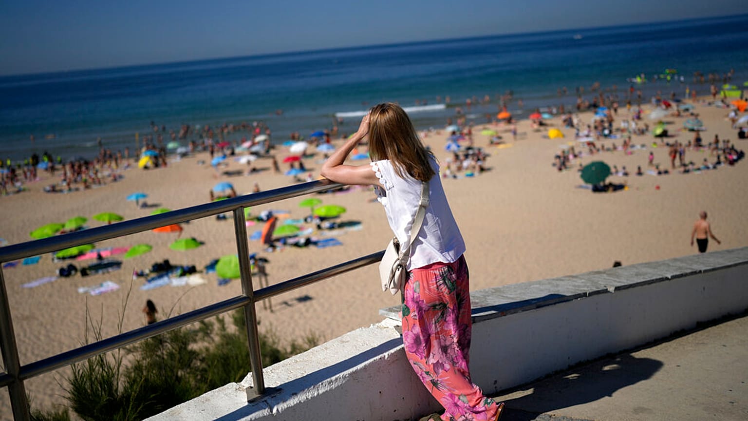 Eine Frau blickt am Freitag, den 8. Juli 2022, auf den Strand von Carcavelos am Stadtrand von Lissabon. 