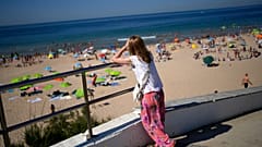 Eine Frau blickt am Freitag, den 8. Juli 2022, auf den Strand von Carcavelos am Stadtrand von Lissabon. 