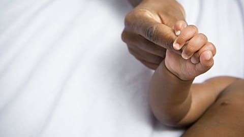 A baby holds a woman's finger.