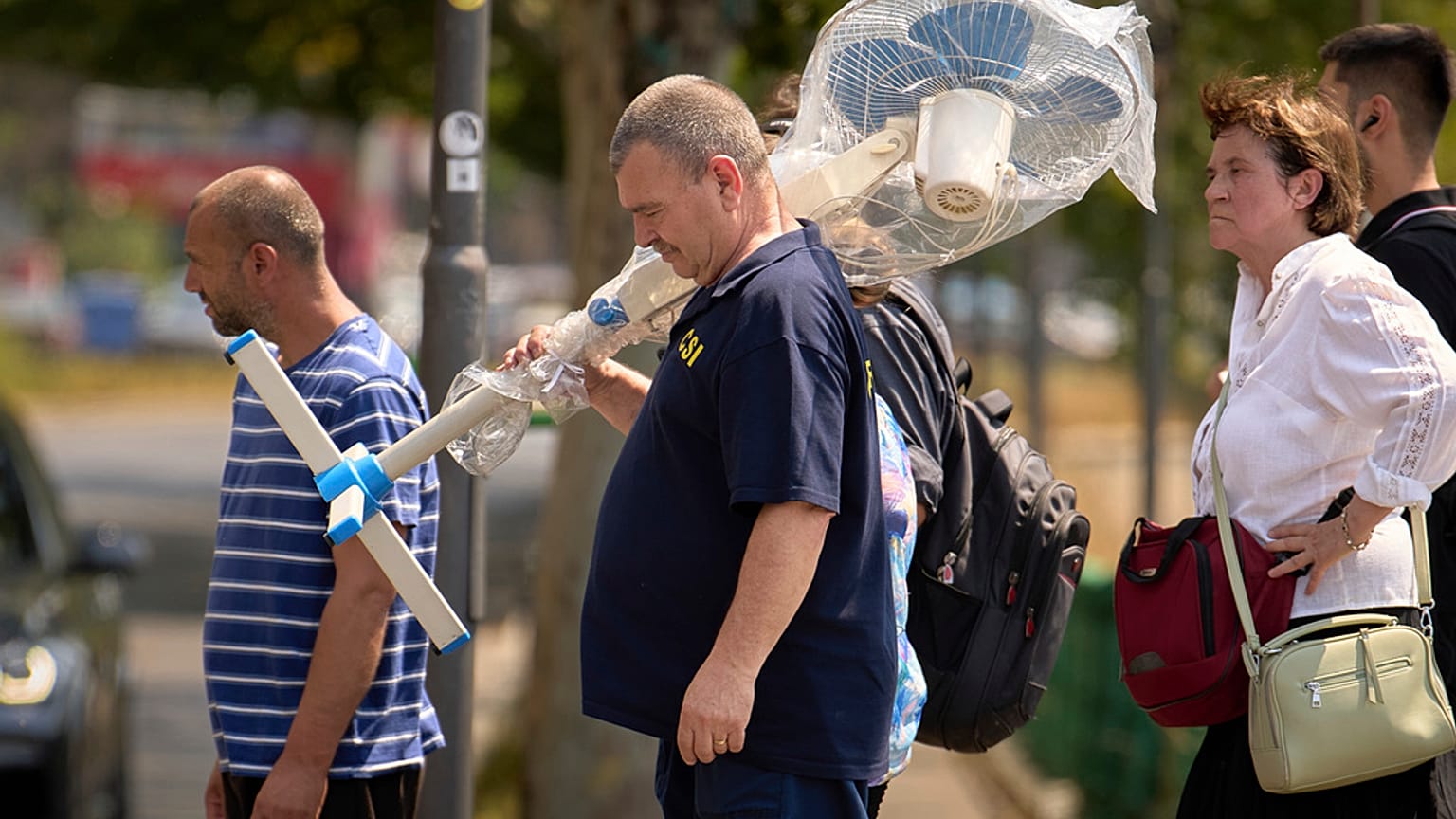 Un uomo trasporta un ventilatore a Bucharest, Romania, 7 luglio 2025