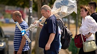 Un uomo trasporta un ventilatore a Bucharest, Romania, 7 luglio 2025