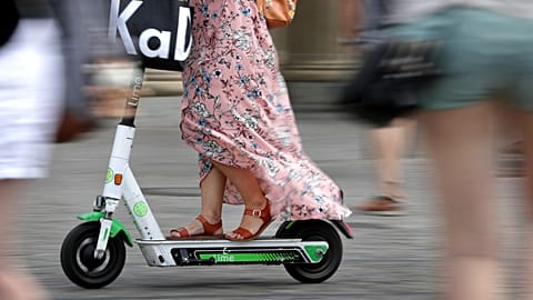 A woman drives an electric Lime scooter through a busy square, Germany, Tuesday, Aug. 6, 2019.